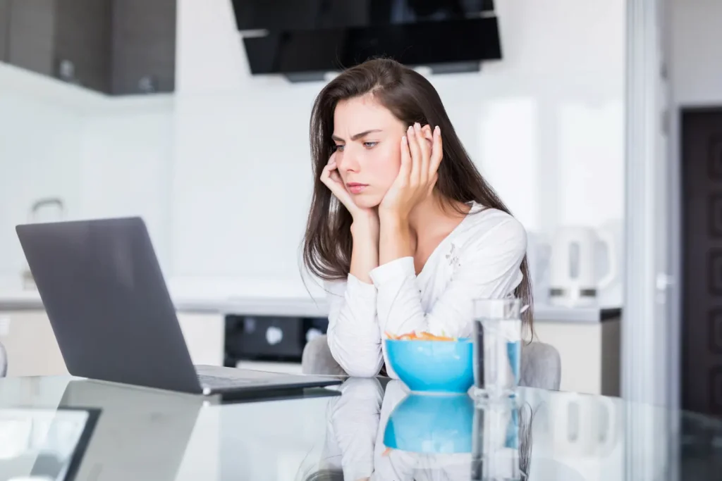 Chica con dolor de mandíbula frente a una laptop